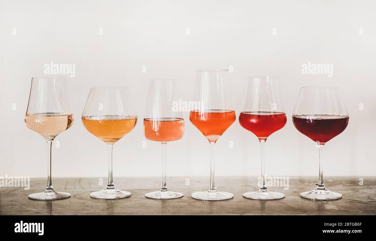Nuancen von Roséwein in Gläsern auf Betontisch Stockfoto
