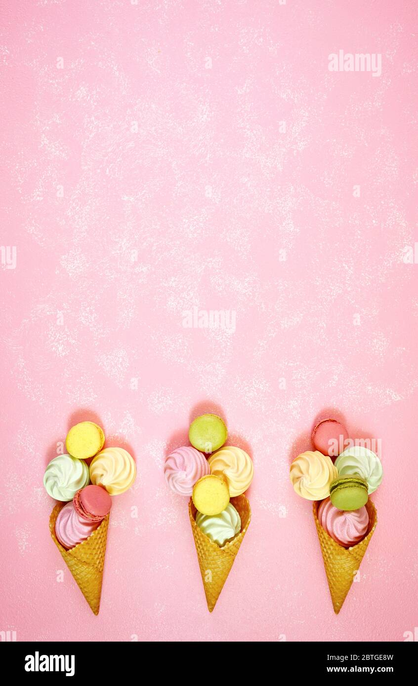 Sommer dekorierte Grenze von Eis-Kegel mit Makronen und Baiser auf rosa strukturierten Hintergrund gefüllt, negative Kopie Raum. Elegantes, flaches Design, Stockfoto