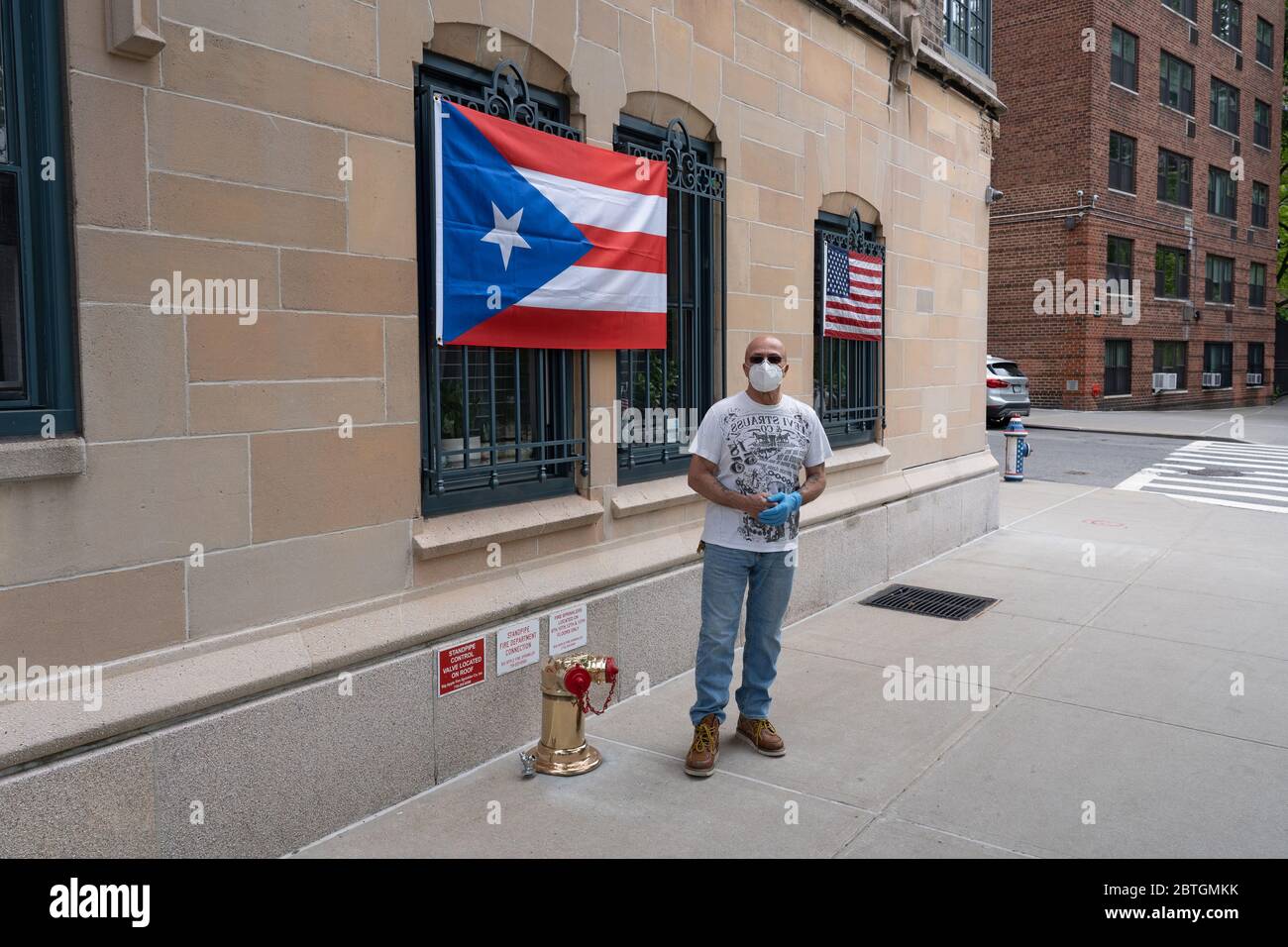 NEW YORK, NEW YORK - 25. MAI 2020: Raymond Miranda zeigt amerikanische und Puerto-ricanische Flaggen am Memorial Day Wochenende vor seiner Wohnung. Stockfoto
