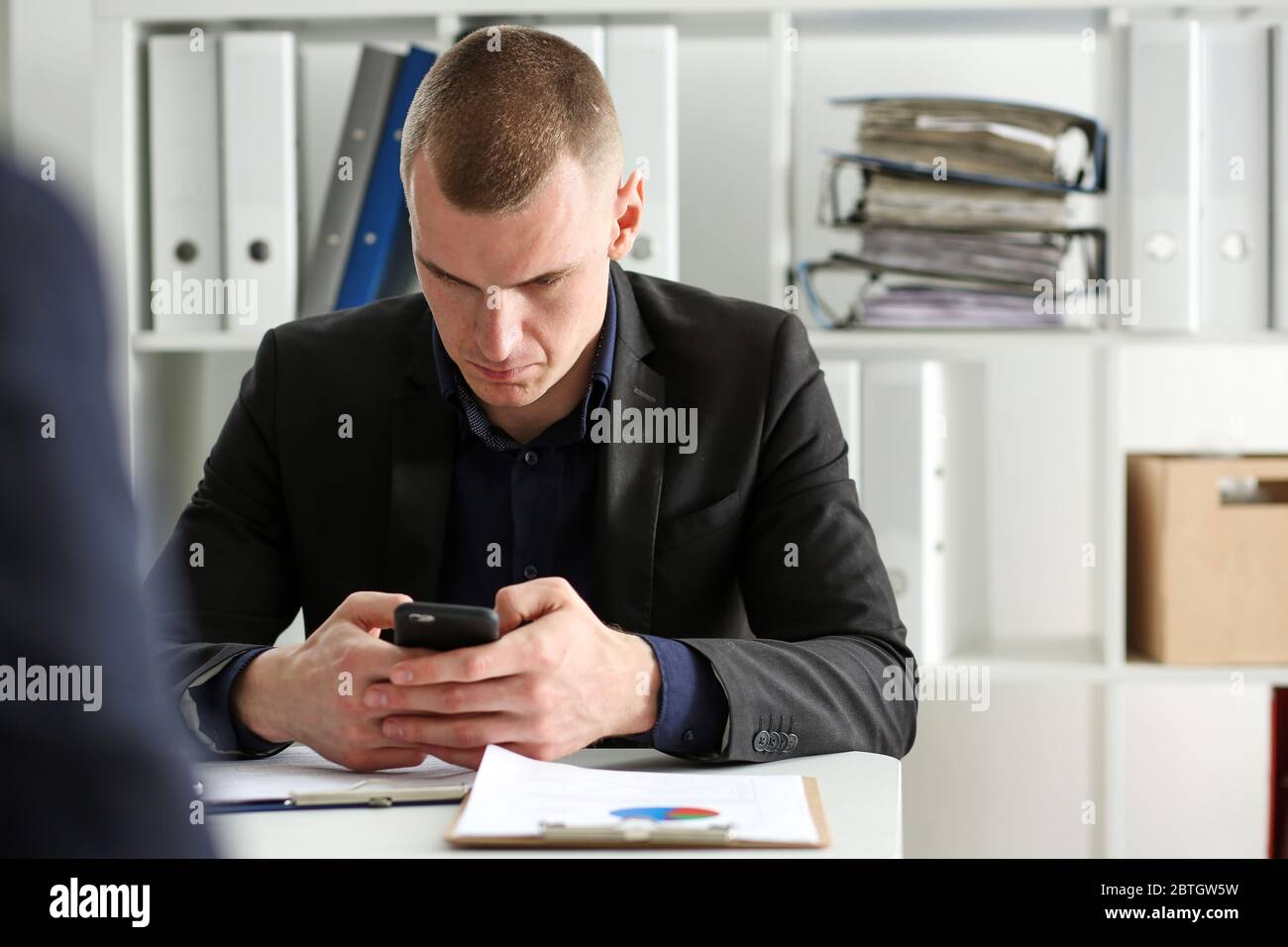 Gut aussehend nachdenklichen Geschäftsmann Blick auf Handy in der Hand Stockfoto
