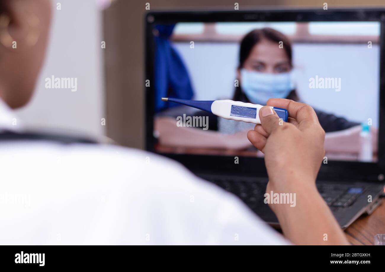Arzt erklärt, wie man Fieberthermometer für Patienten durch Online-auf Laptop verwenden - Konzept der Online-Chat, Teleheattung, oder Teleberatung mit Stockfoto