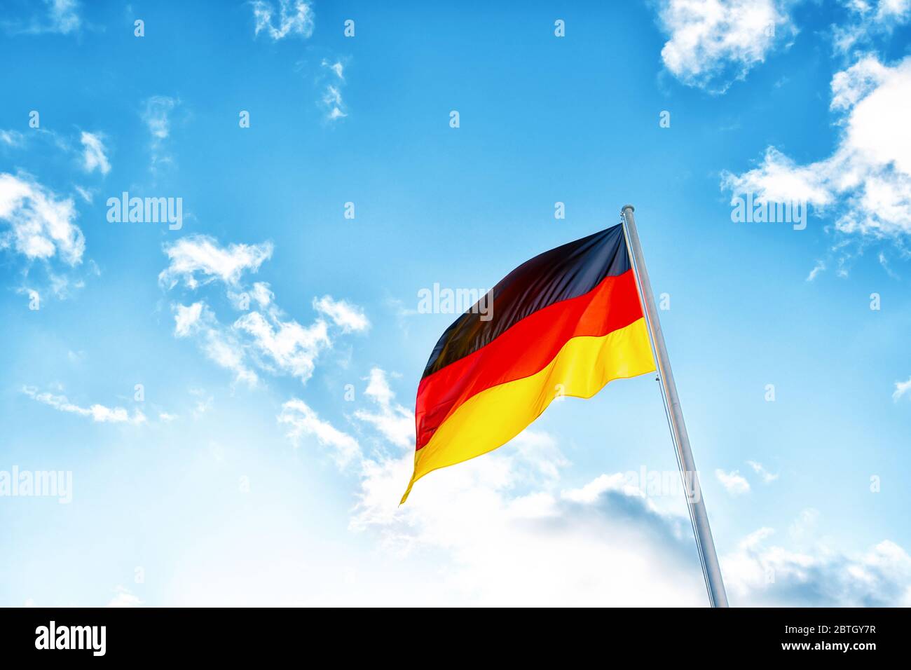 Eine deutsche Flagge mit schwarzen, roten und gelben Streifen vor Wolken in blauem Himmel Stockfoto