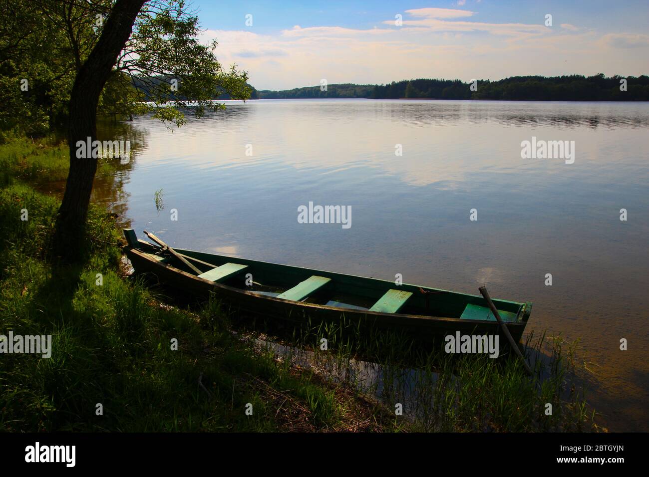Ein kleines Holzboot am Ufer eines Sees während eines ruhigen, klaren Sommertages mit nahem Sonnenuntergang. Im Nationalpark Aukštaitija in Litauen. Stockfoto