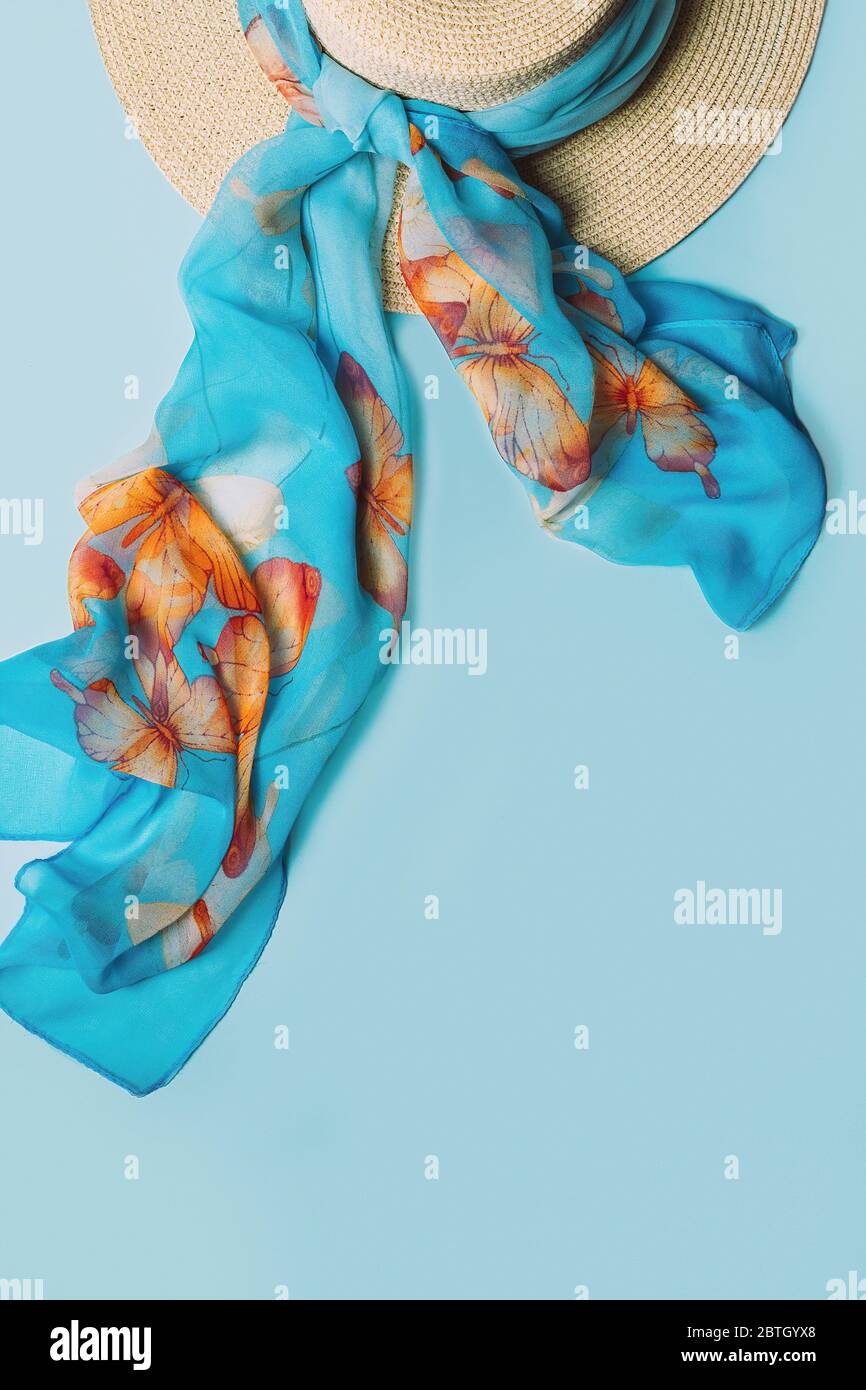 Strohhut mit Schal auf blauem Hintergrund. Sommer Mode flach legen, Ansicht von oben mit Kopierraum. Stockfoto