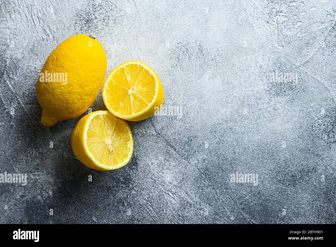 Ganze und geleckte Hälfte Obst Zitrone und auf grauem Hintergrund mit Platz für Text. Stockfoto
