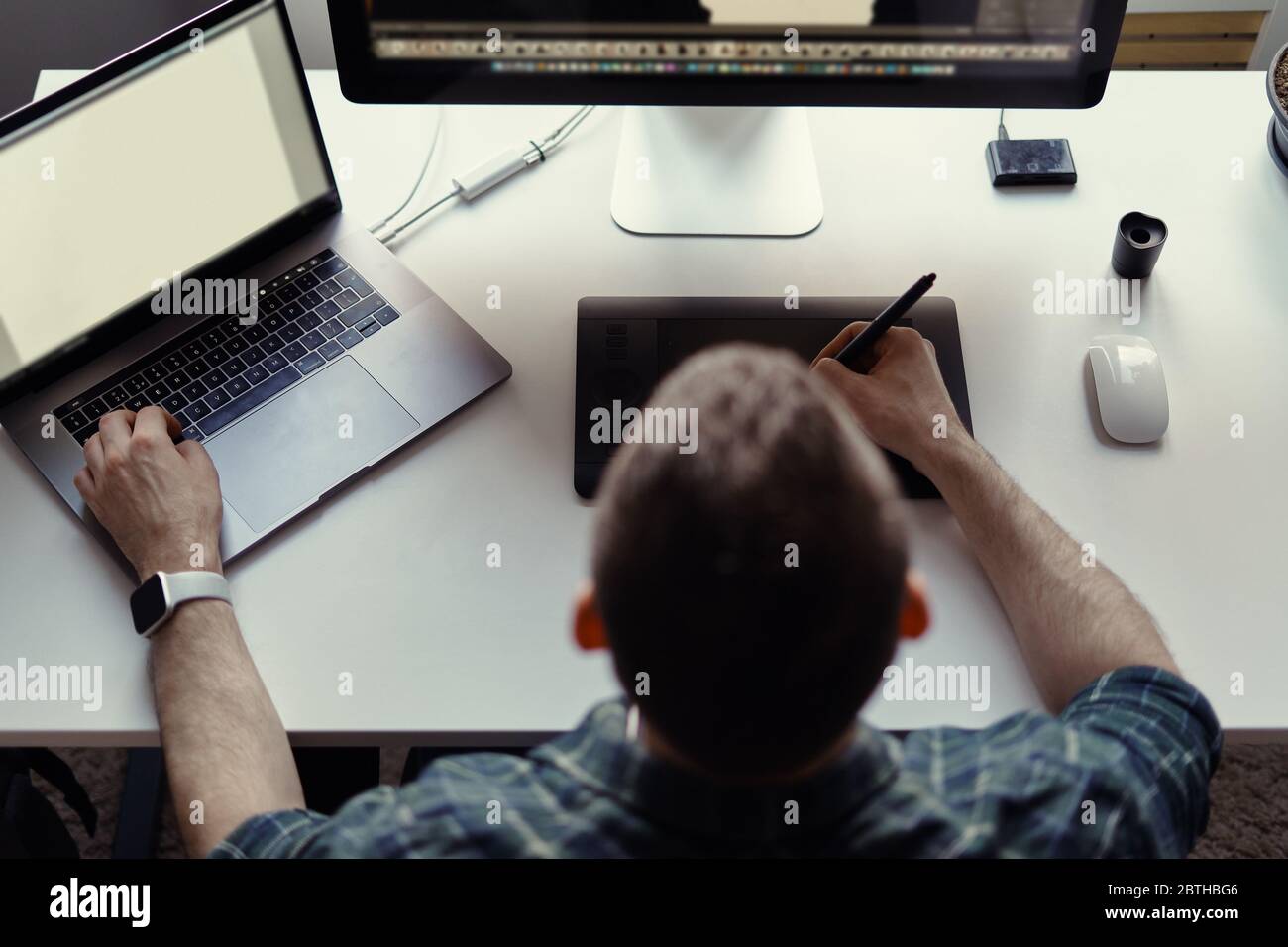 Grafikdesigner Arbeiten mit interaktivem Stift-Display, digitalem Zeichentablett und Stift auf einem Computer mit leerem Monitor während der Smart-Watch. Stockfoto