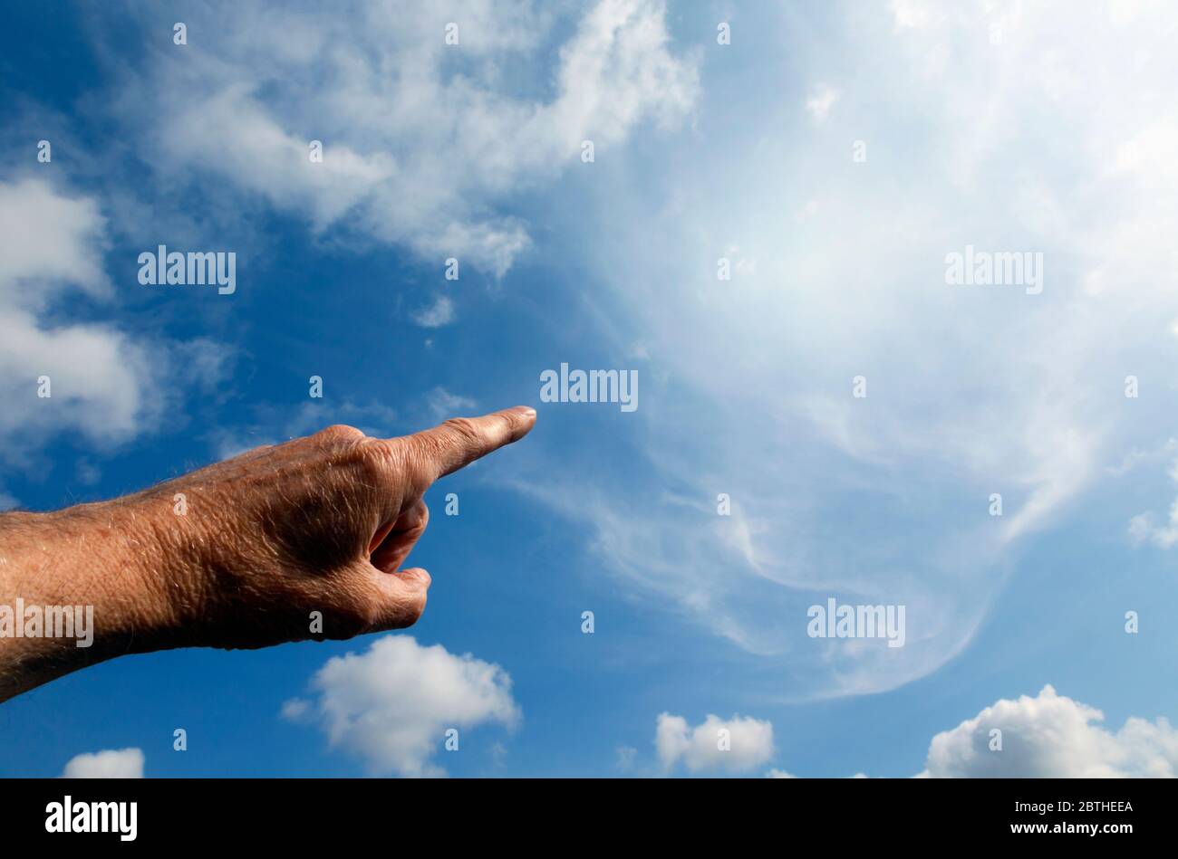 Finger zeigt auf helle, seltsam geformte Wolke am Himmel. Stockfoto