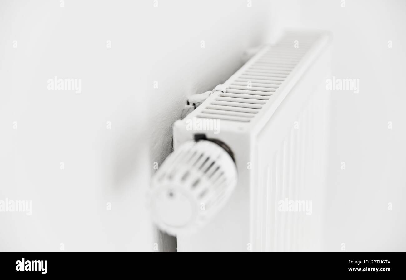 Heizung mit einem weißen Panel-Heizkörper und Thermostat an der Wand einer Wohnung Stockfoto