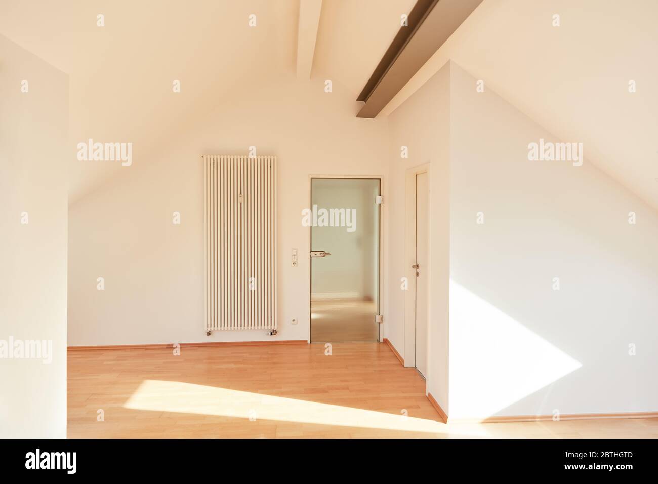 Tür und Heizung in einem hellen leeren Raum der Dachwohnung Stockfoto