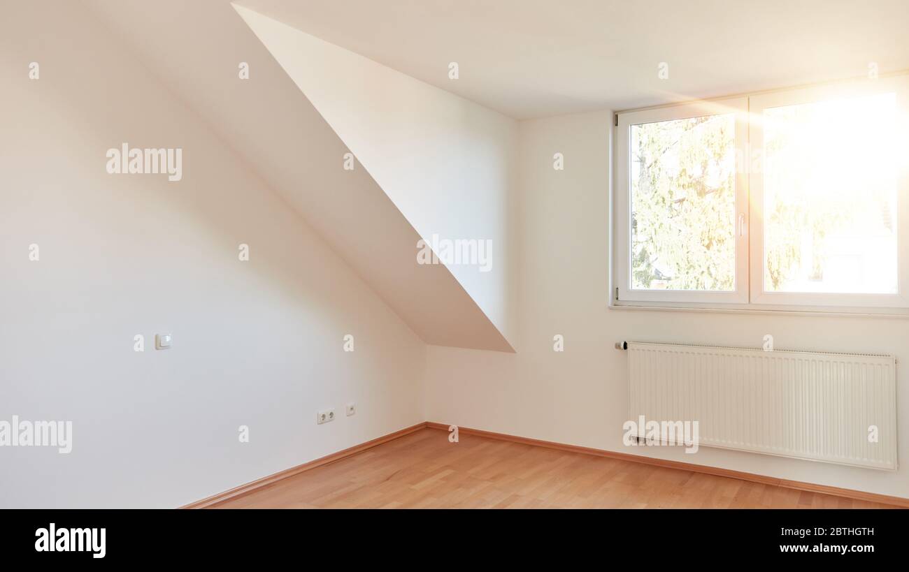 Dachschräge in leerem weißen Zimmer in hellen sonnigen Dachgeschoss Wohnung Stockfoto