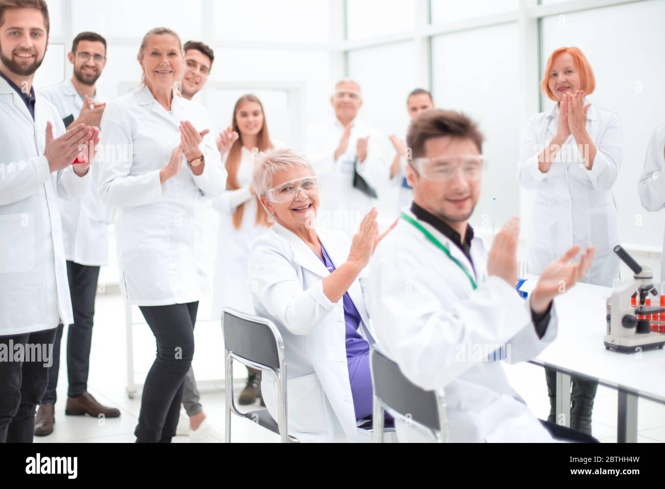 Eine Gruppe junger Wissenschaftler gratuliert ihrem Kollegen mit Applaus Stockfoto