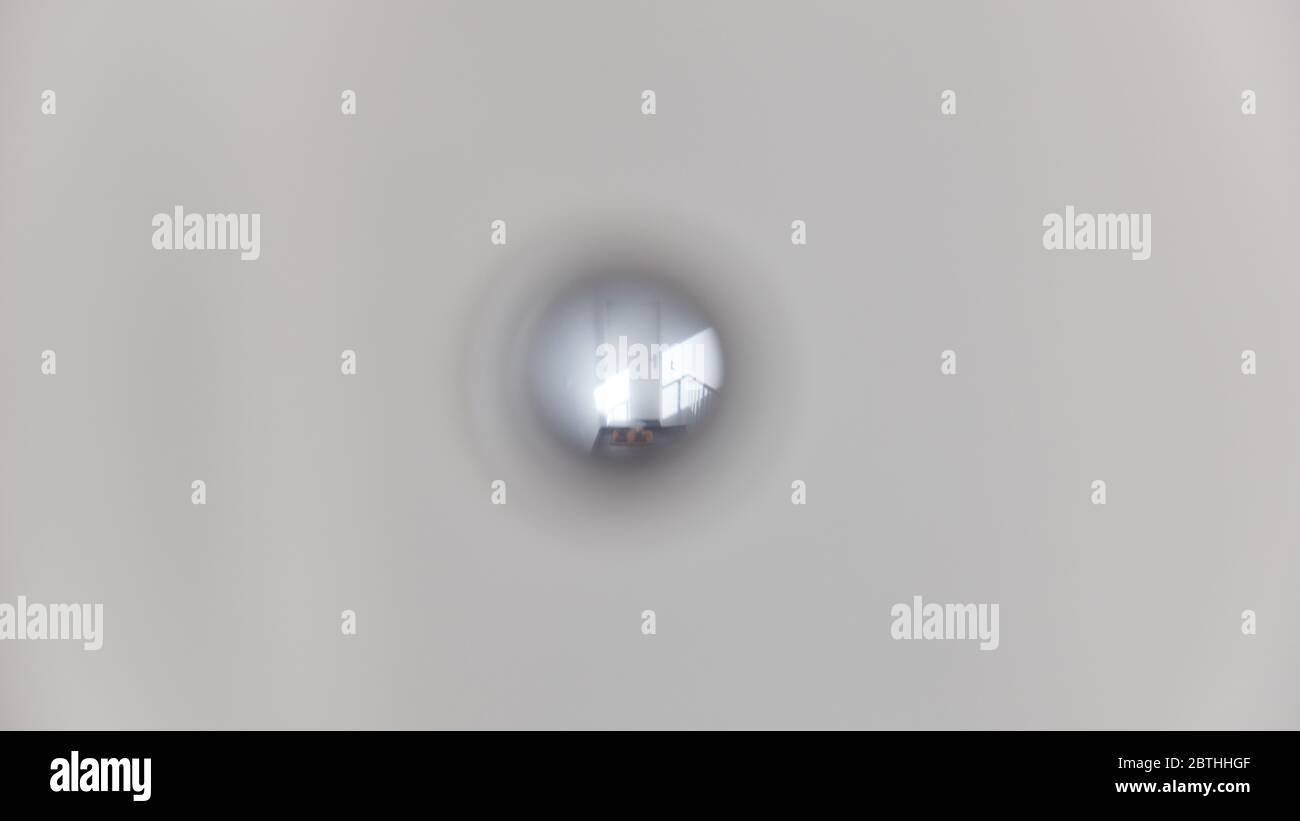 Blick durch ein Guckloch auf eine helle Wohnungstür in einen leeren Flur Stockfoto
