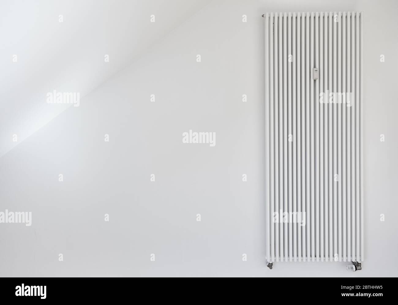 Weißer Heizkörper mit langem Röhrenstrahler an der Wand einer Wohnung Stockfoto