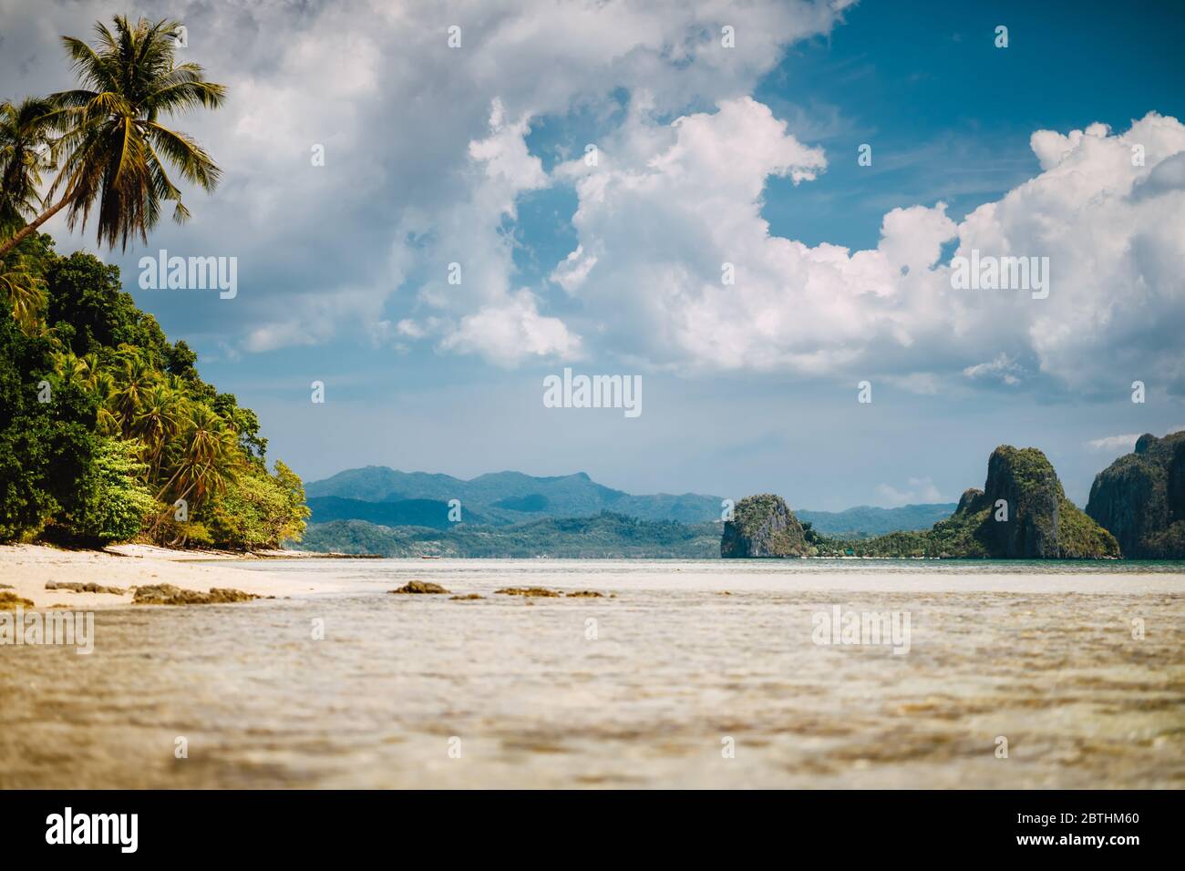 El Nido, Palawan, Philippinen. Landschaftlich schöne tropische Landschaft mit seichter Lagune, Sandstrand mit Palmen. Exotische Inseln und weiße Wolkenlandschaft Stockfoto