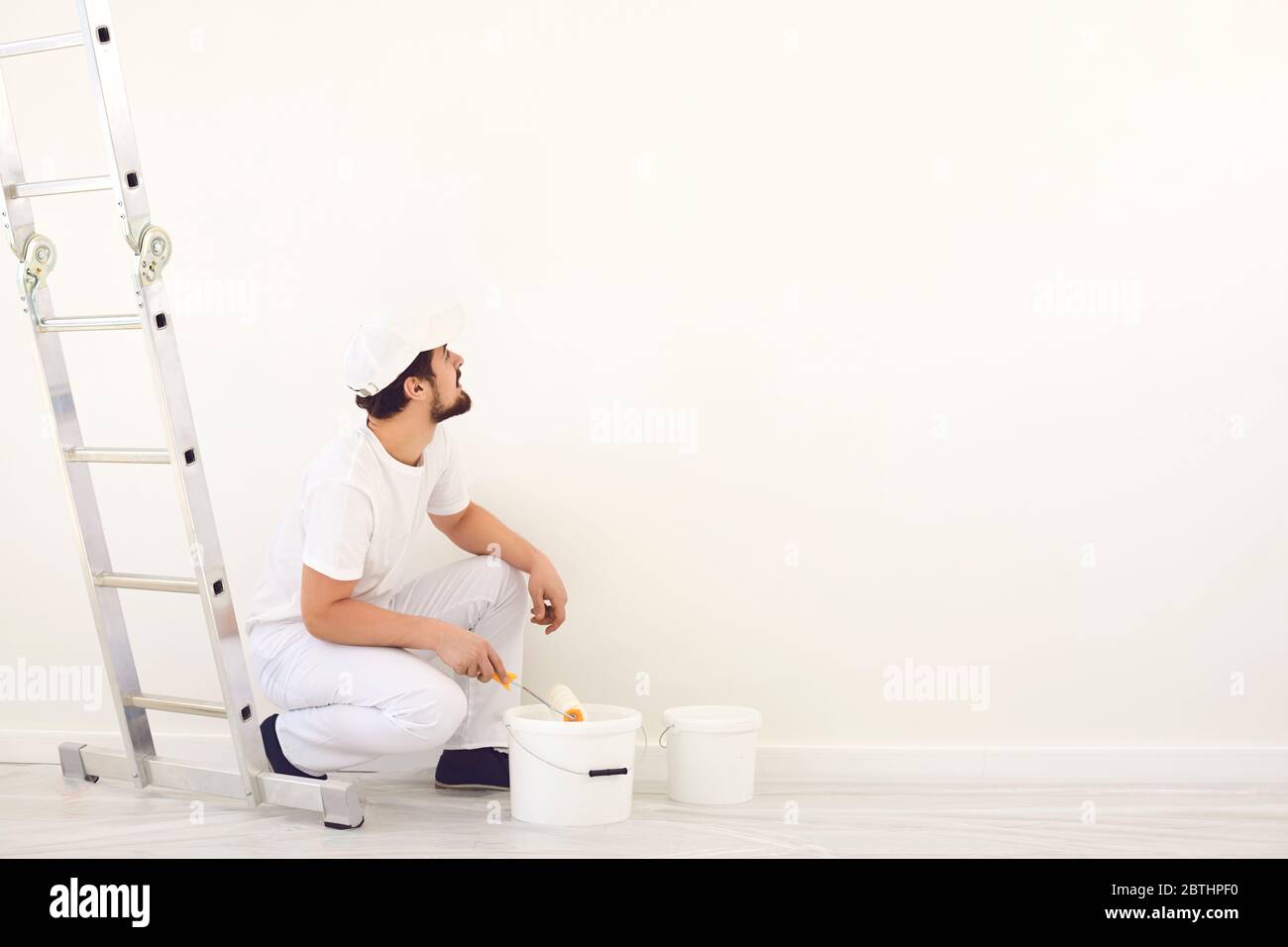 Hausmaler in weißer Uniform auf weißem Hintergrund für die Malerei im Raum. Stockfoto