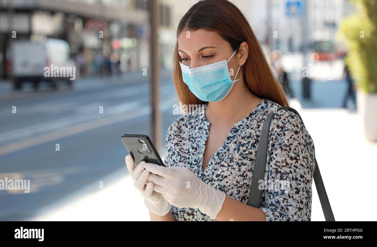 COVID-19 Frau trägt chirurgische Maske und Schutzhandschuhe mit Handy-Anwendung in City Street zu helfen, Kontakt-Tracing und Selbstdiagnose in Stockfoto