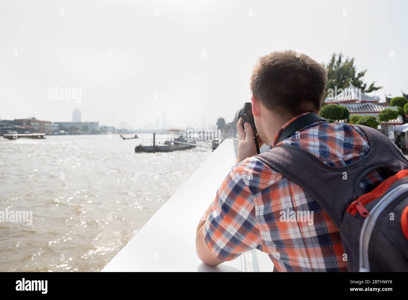 Junger Reisender oder Fotograf geht Sightseeing machen ein Foto von Fluss in Bangkok. Fotografie und Tourismus Konzept. Tourist macht Foto von citysca Stockfoto