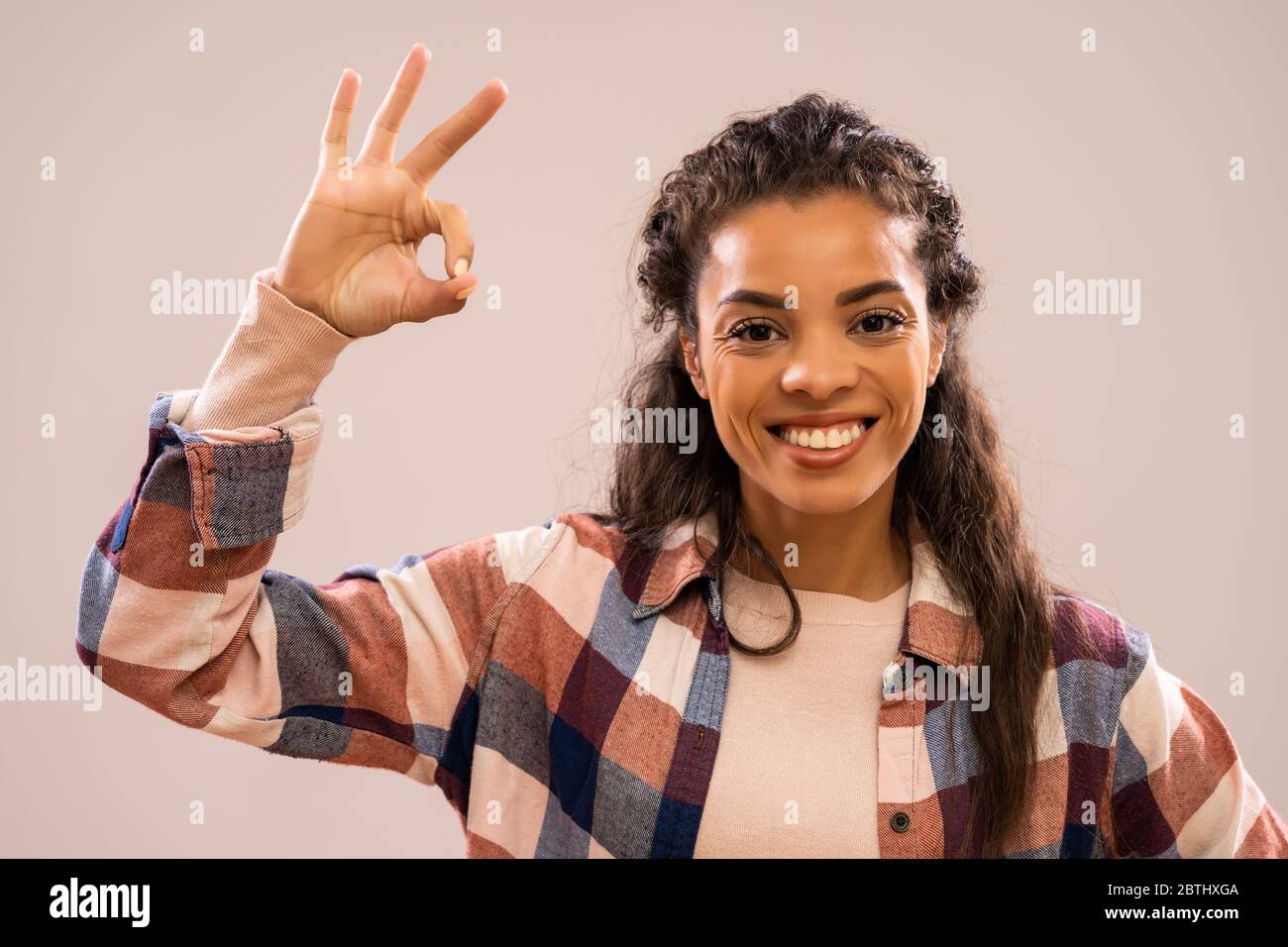 Studio-Aufnahme Porträt der schönen glücklich afroamerikanischen Ethnizität Frau in Freizeitkleidung zeigt ok Hand Zeichen. Stockfoto