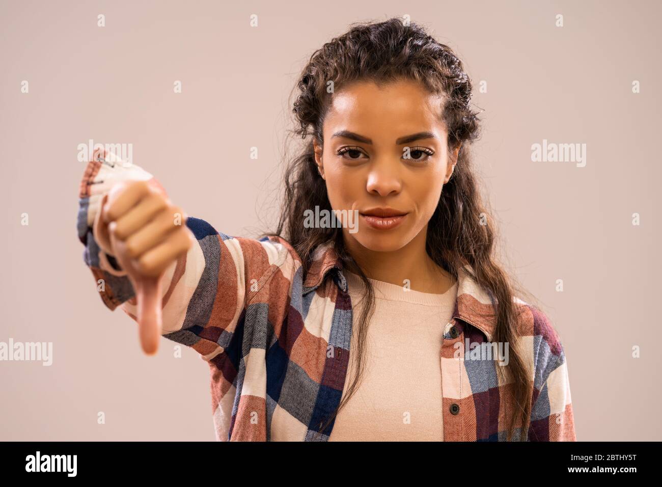 Studio-Aufnahme Porträt der schönen afroamerikanischen Ethnizität Frau mit Daumen nach unten. Stockfoto