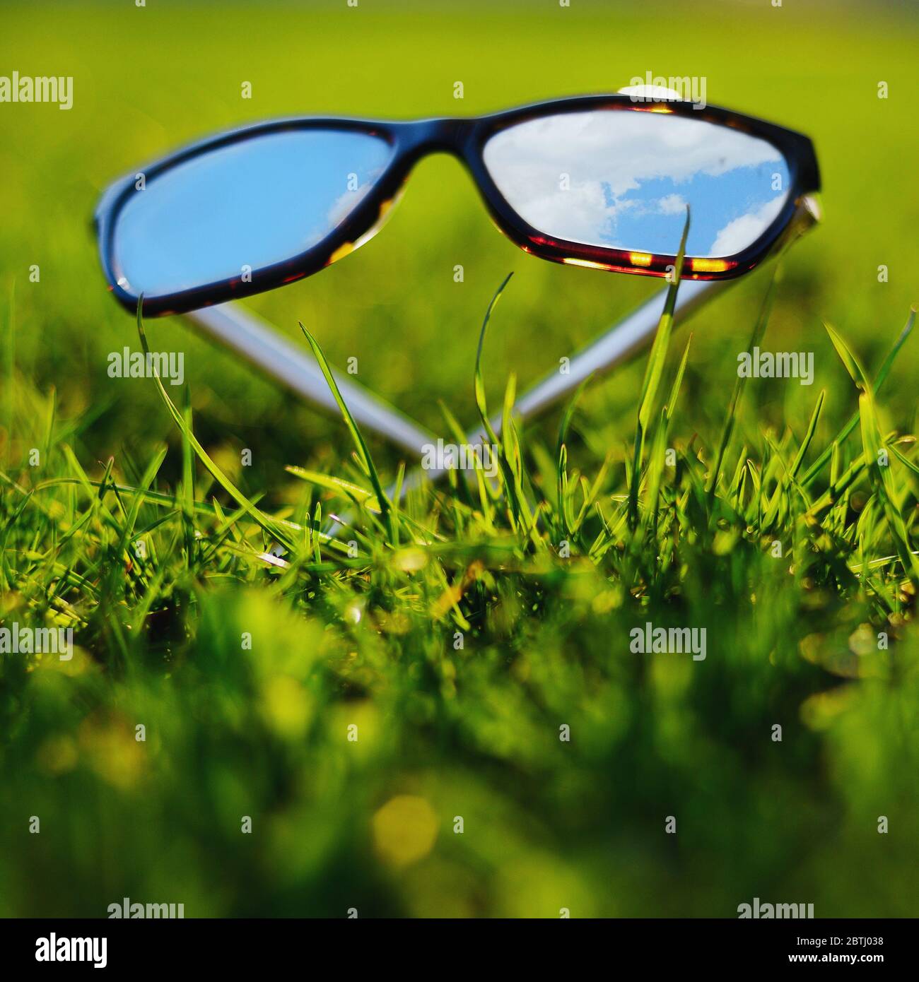 Sonnenbrille liegend Gras spiegelt den blauen Himmel Stockfoto