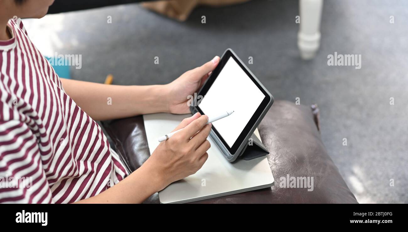 Zugeschnittenes Bild von kreativen Mann Zeichnung auf Computer-Tablet mit Stift während sitzen auf der Ledercouch mit ruhigen Wohnzimmer als Hintergrund. Stockfoto