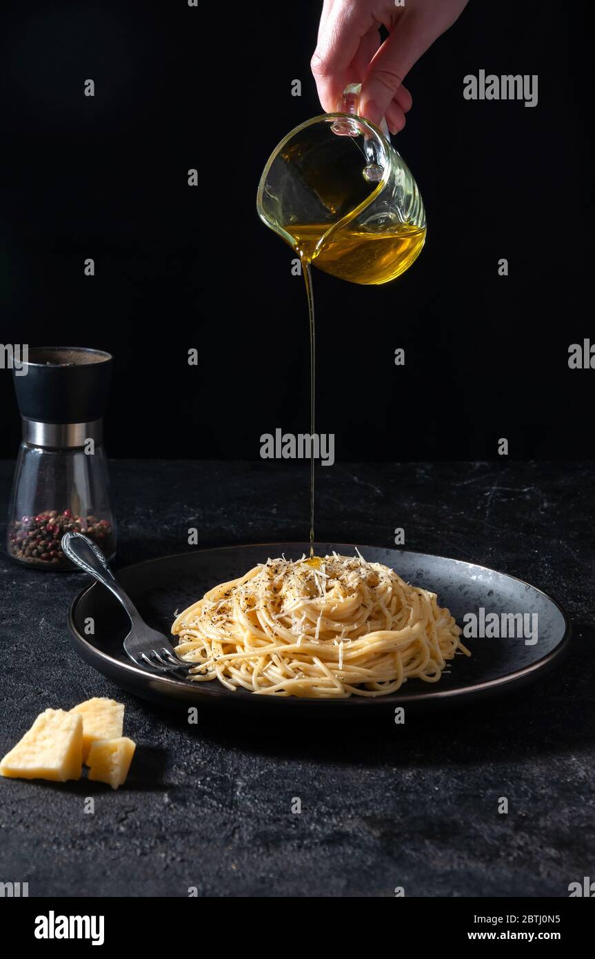 Cacio e Pepe – Italienische Pasta mit Käse und Pfeffer. Spaghetti gegossen Olivenöl auf schwarzen Teller auf dunklen Hintergrund. Stockfoto