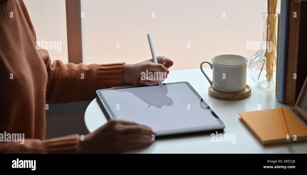 Nahaufnahme Frau Zeichnung / Skizzieren auf Computer-Tablet mit einem Stift, während sie am Schreibtisch sitzen über bequem. Stockfoto