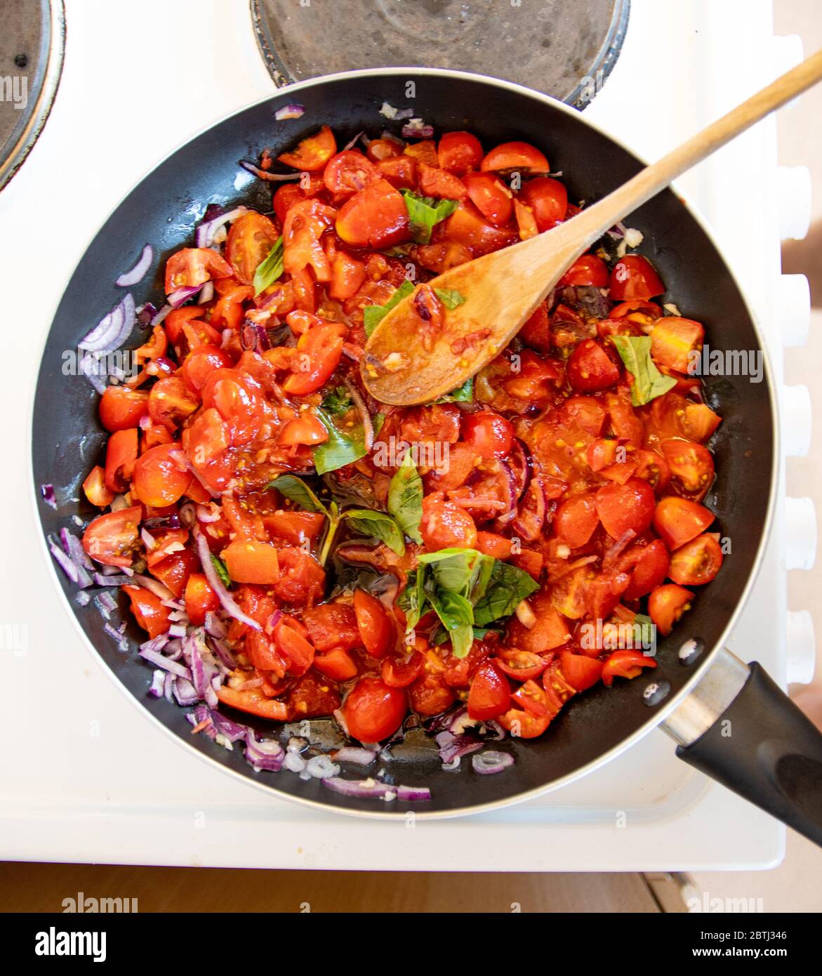 Köstliche hausgemachte Tomaten und Basilikum Pasta-Sauce auf dem Kochfeld köcheln und kochen Stockfoto
