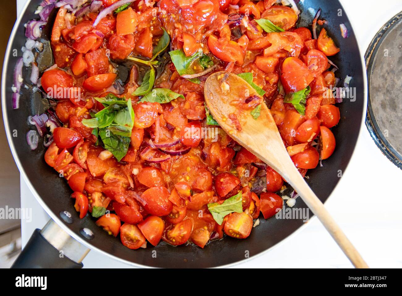 Köstliche hausgemachte Tomaten und Basilikum Pasta-Sauce auf dem Kochfeld köcheln und kochen Stockfoto