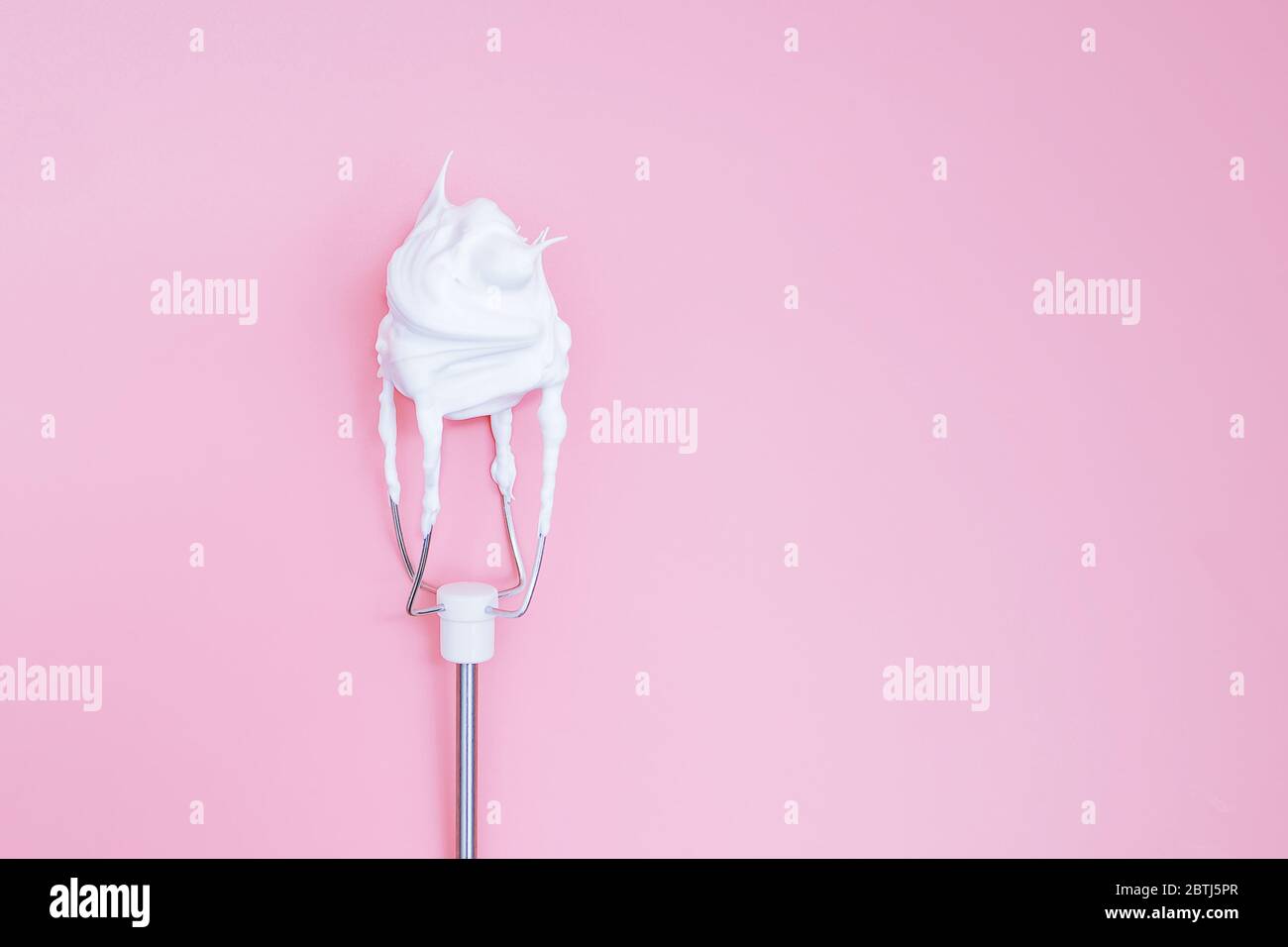 Schlagen Sie auf dem Mixer das Eiweiß auf einem rosa Hintergrund Stockfoto
