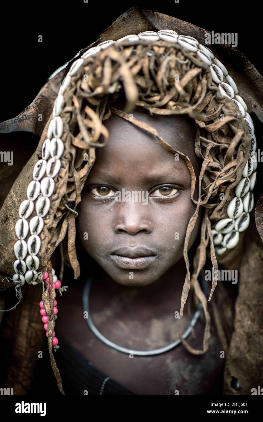 Ein junger Tribes Junge trägt eines ihrer schrulligen Modestücke. LONDONDERRY, NORDIRLAND, Großbritannien: FASZINIERENDE Fotografien zeigen das Alter der Suri-Stämme Stockfoto