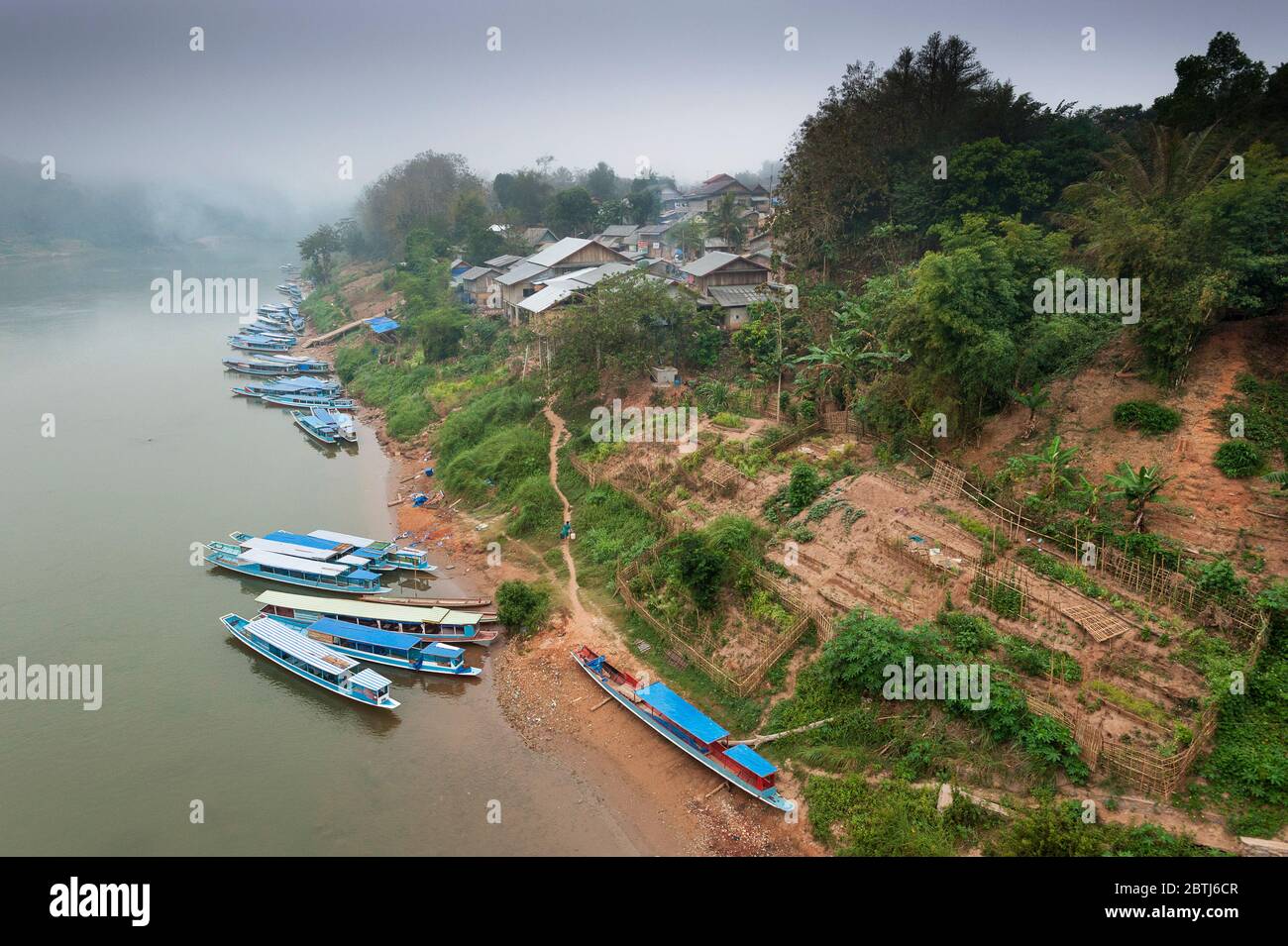 Langsame Holzboote auf dem Mekong-Fluss während eines nebligen Morgens, Nord-Laos, Südostasien Stockfoto