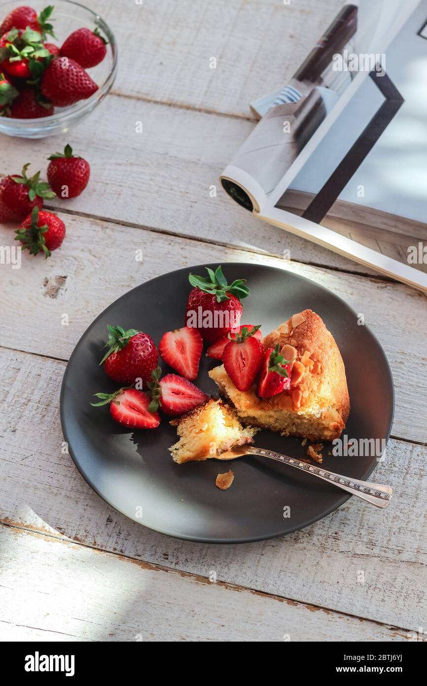 Eine Scheibe hausgemachter Kuchen mit frischen Erdbeeren auf einem weißen Holztisch Stockfoto