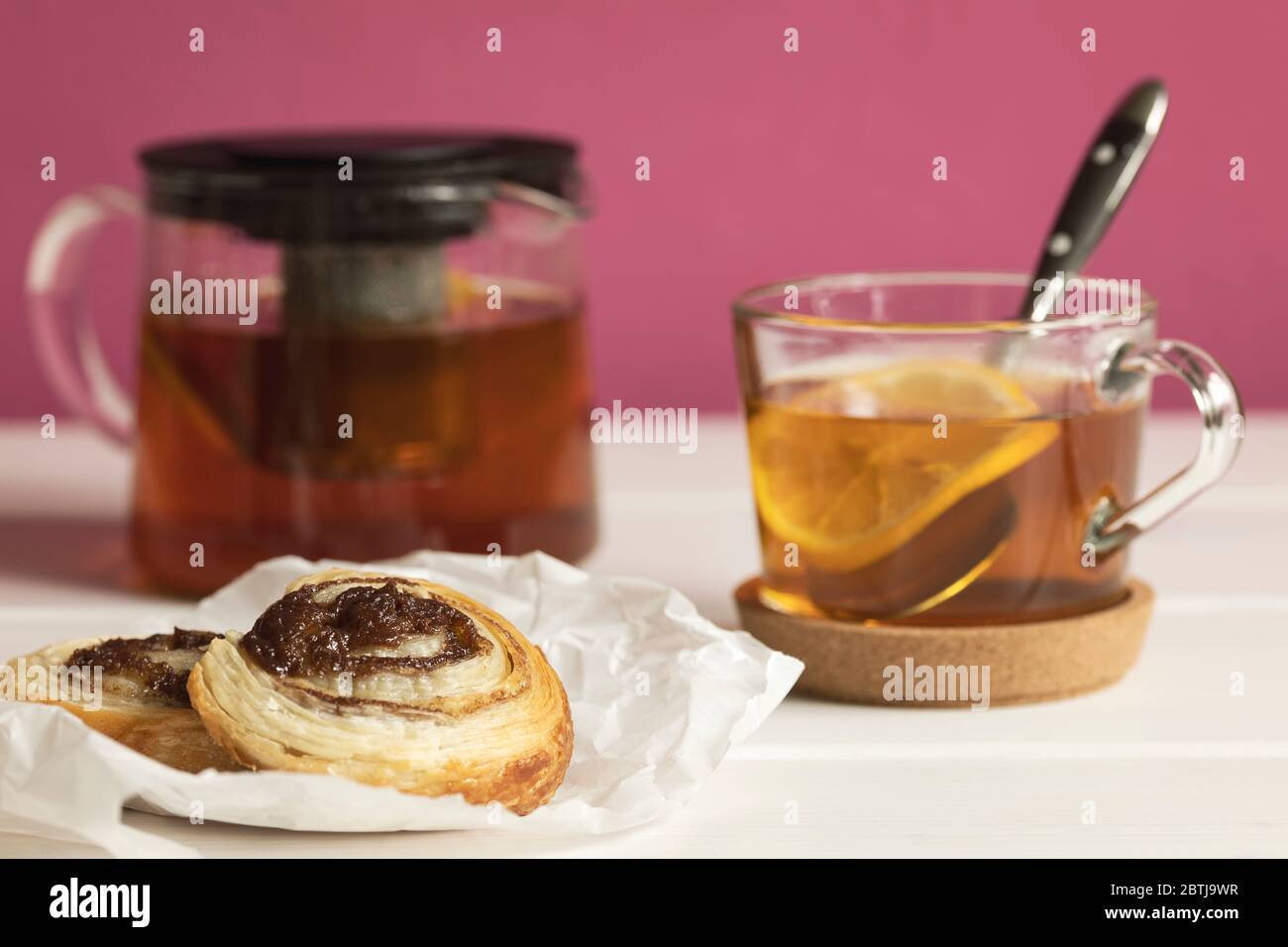 Hausgemachte Blätterteig Zimtbrötchen serviert mit schwarzem Tee mit Zitrone als Frühstück. Stockfoto