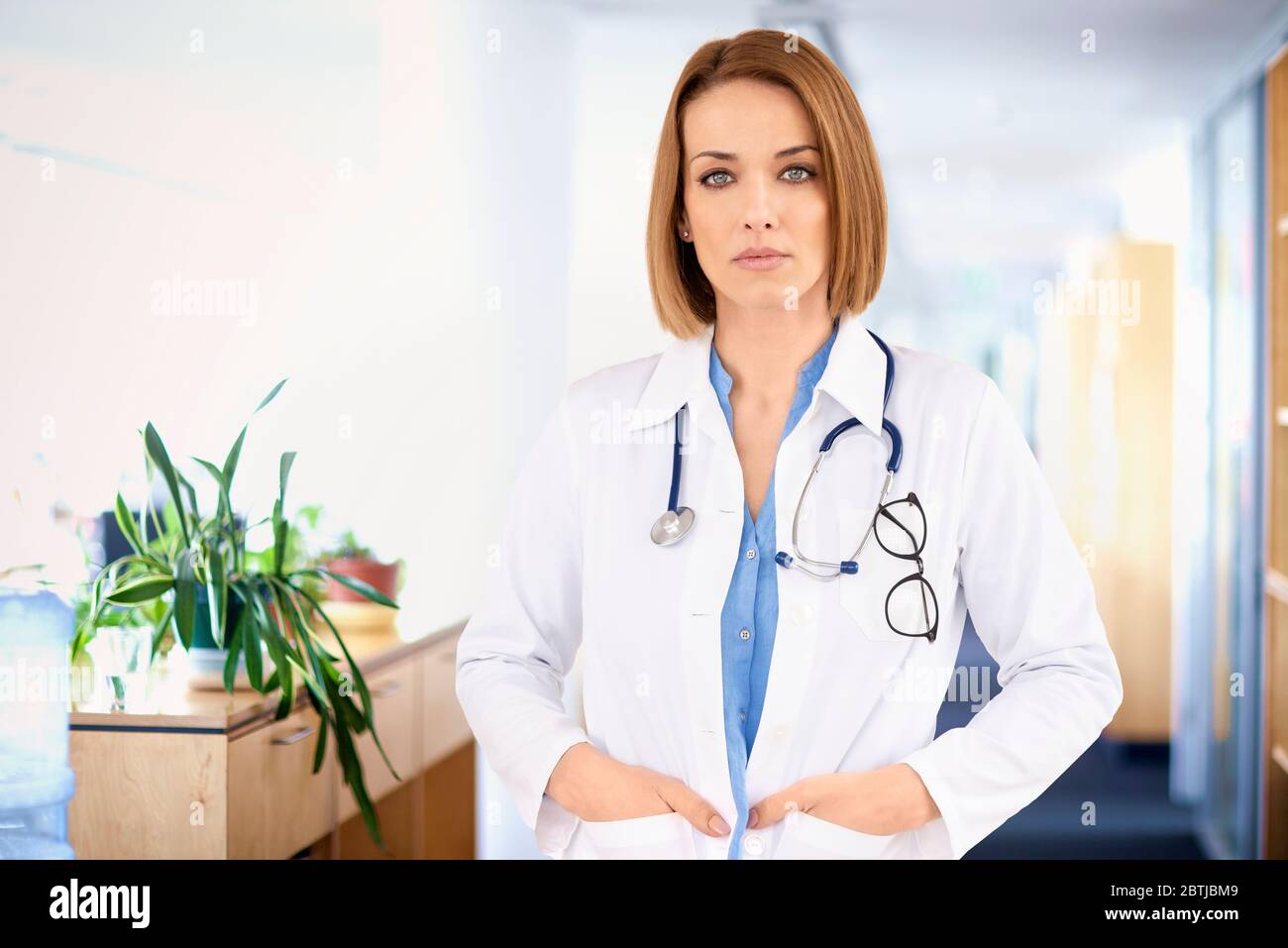 Porträtaufnahme einer selbstbewussten Ärztin, die im Krankenhausskorridor auf die Kamera schaut. Stockfoto