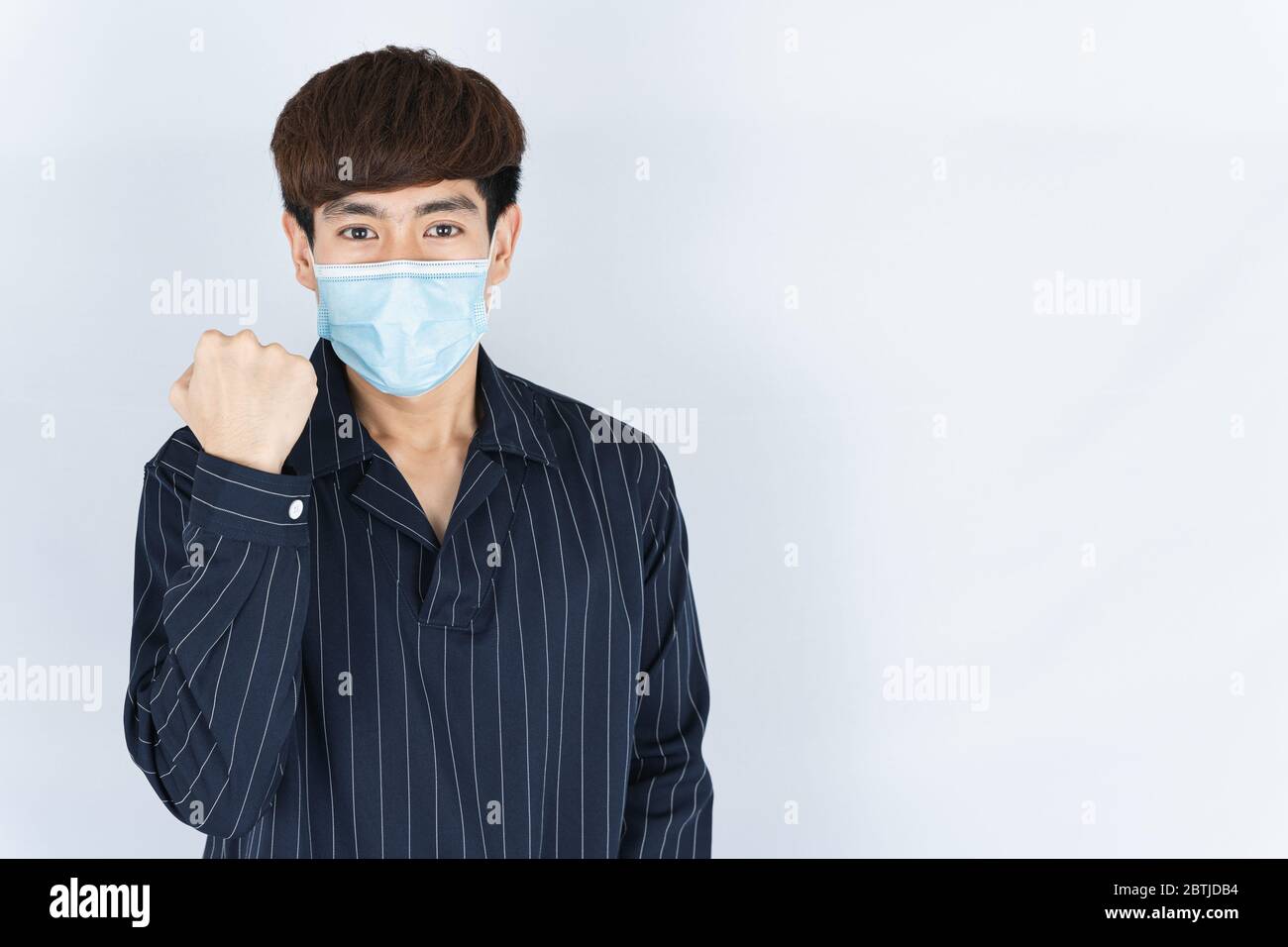 Asian gut aussehend glücklich Hipster Mann trägt eine medizinische Schutz Gesichtsmaske zum Schutz der Coronavirus, Filter Staub PM 2.5 und Kälte und heben ihre Hand zu Stockfoto