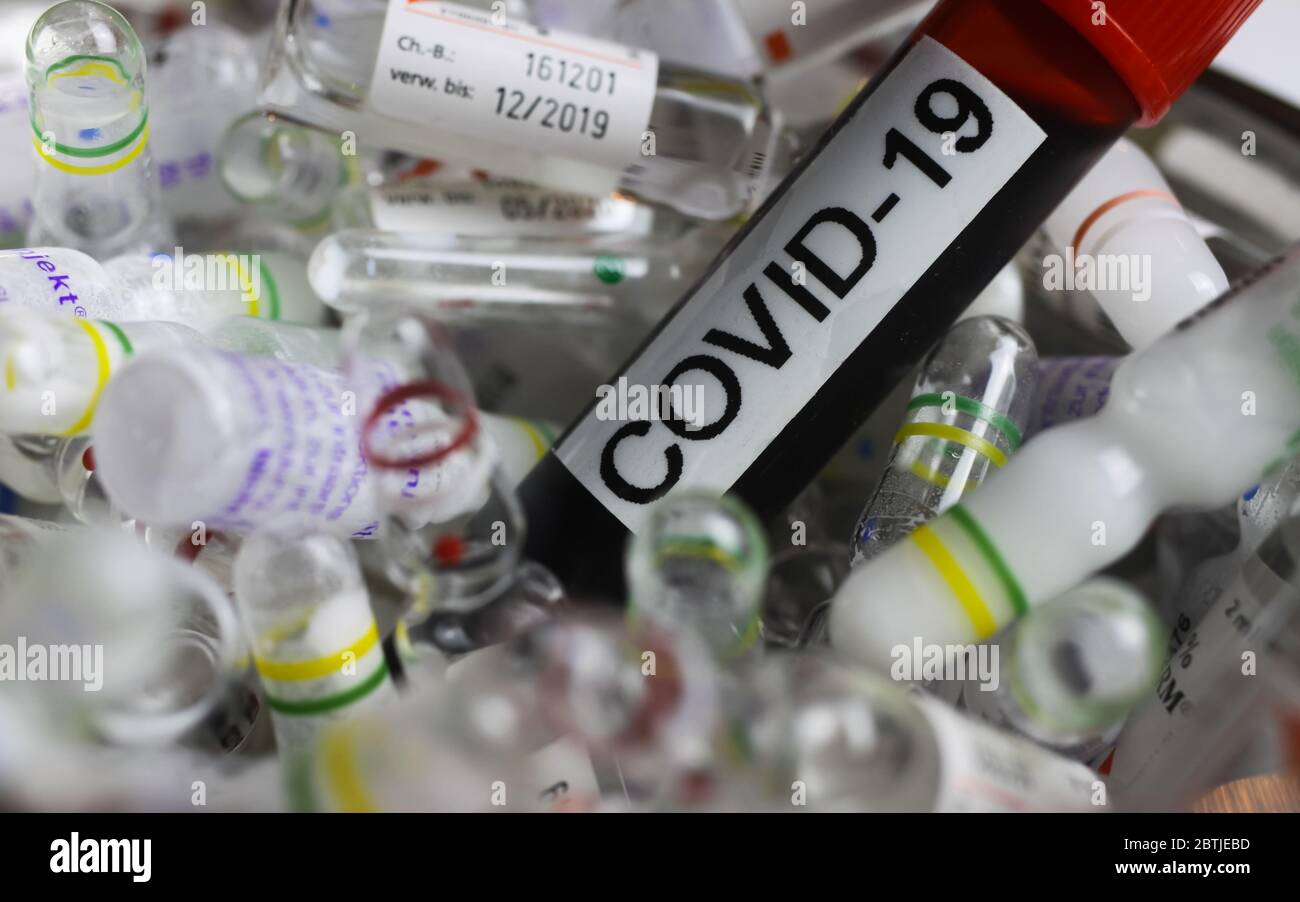 Viersen, Deutschland - Mai 26. 2020: Nahaufnahme der Blutprobenflasche mit Text covid-19 auf einem Haufen von Drogenampullen (Fokus auf Blutgefäß) Stockfoto