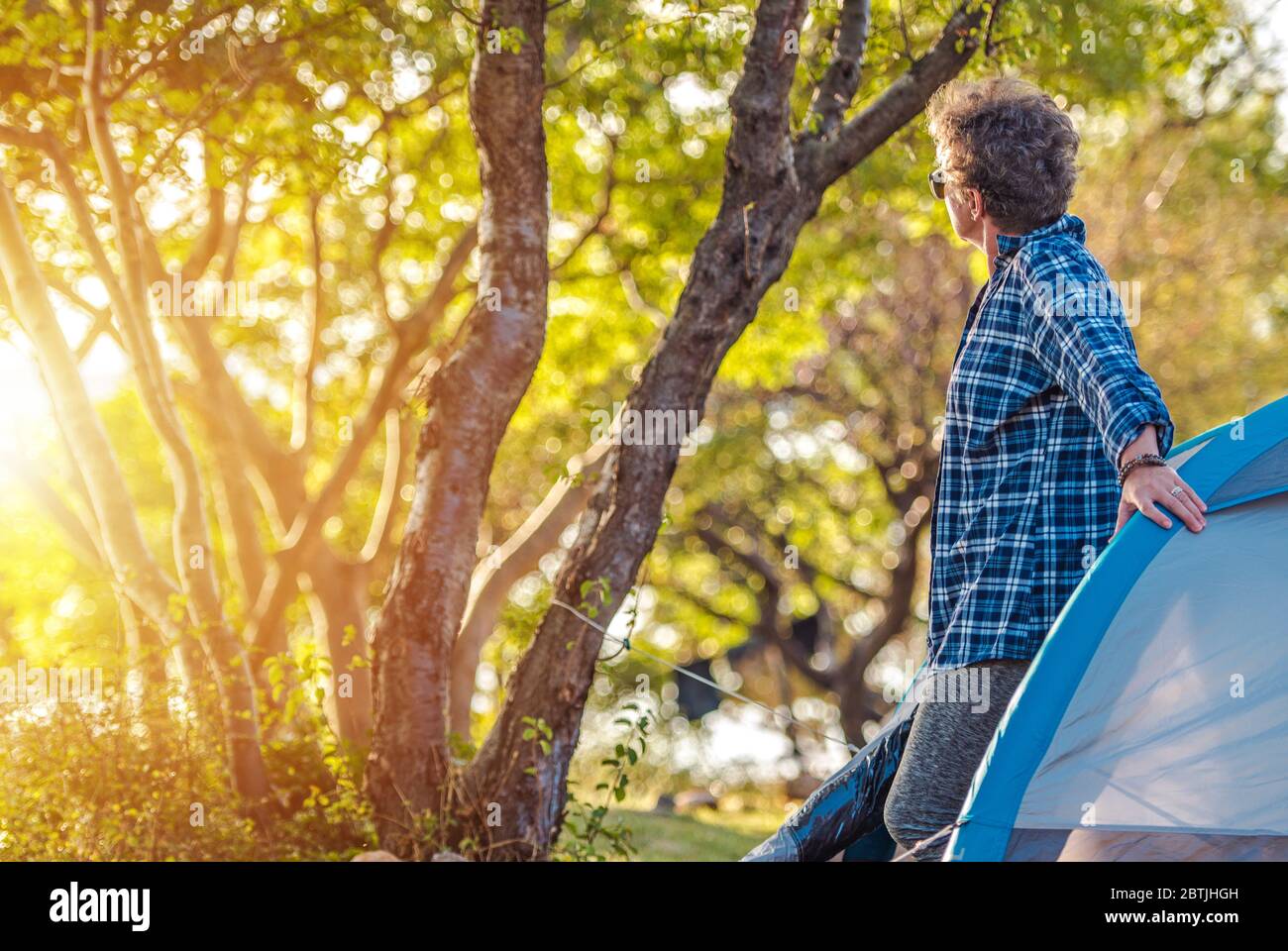 Kaukasische Frau in ihren 60er Jahren genießen ihren Urlaub während des heißen Sommertages. Outdoor und Erholung Thema. Zelt und Camping. Stockfoto