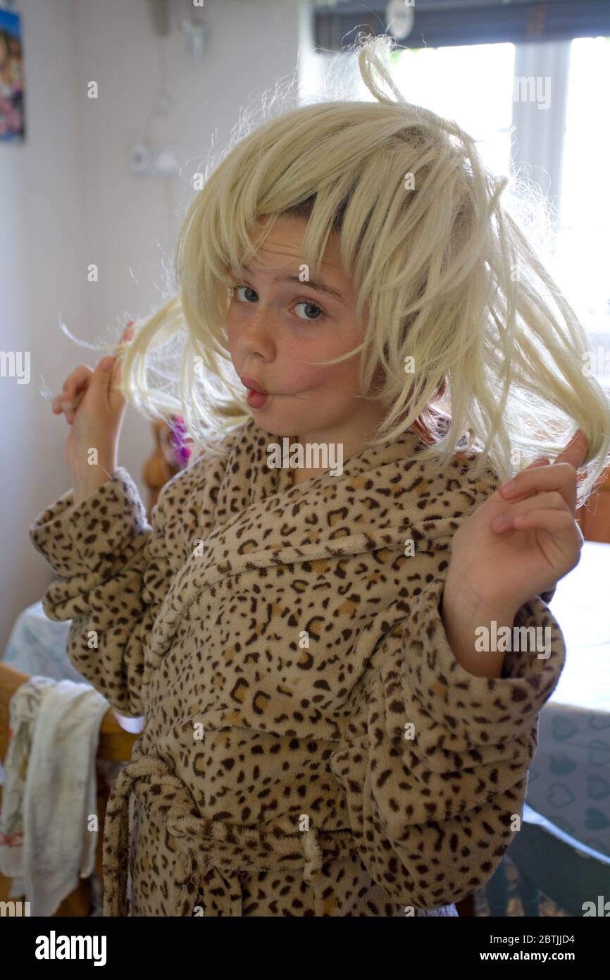 Junges Mädchen in Leopardenmuster Morgenmantel trägt eine blonde Perücke Stockfoto