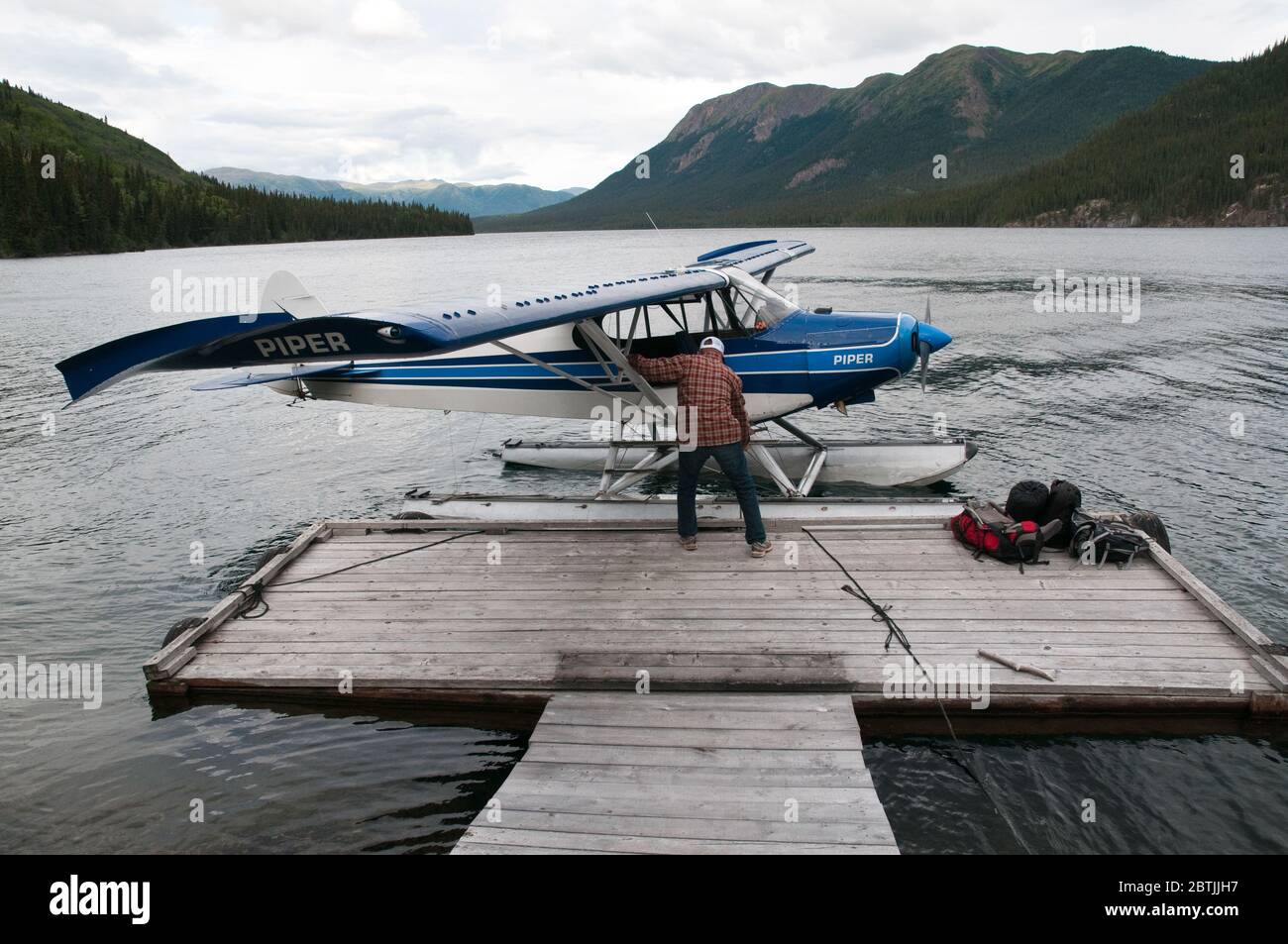 Ein einmotoriger, zweisitziger Wasserflugzeug und Pilot des Piper Cub auf einem See im Spatsizi Plateau Wilderness Provincial Park in British Columbia, Kanada. Stockfoto