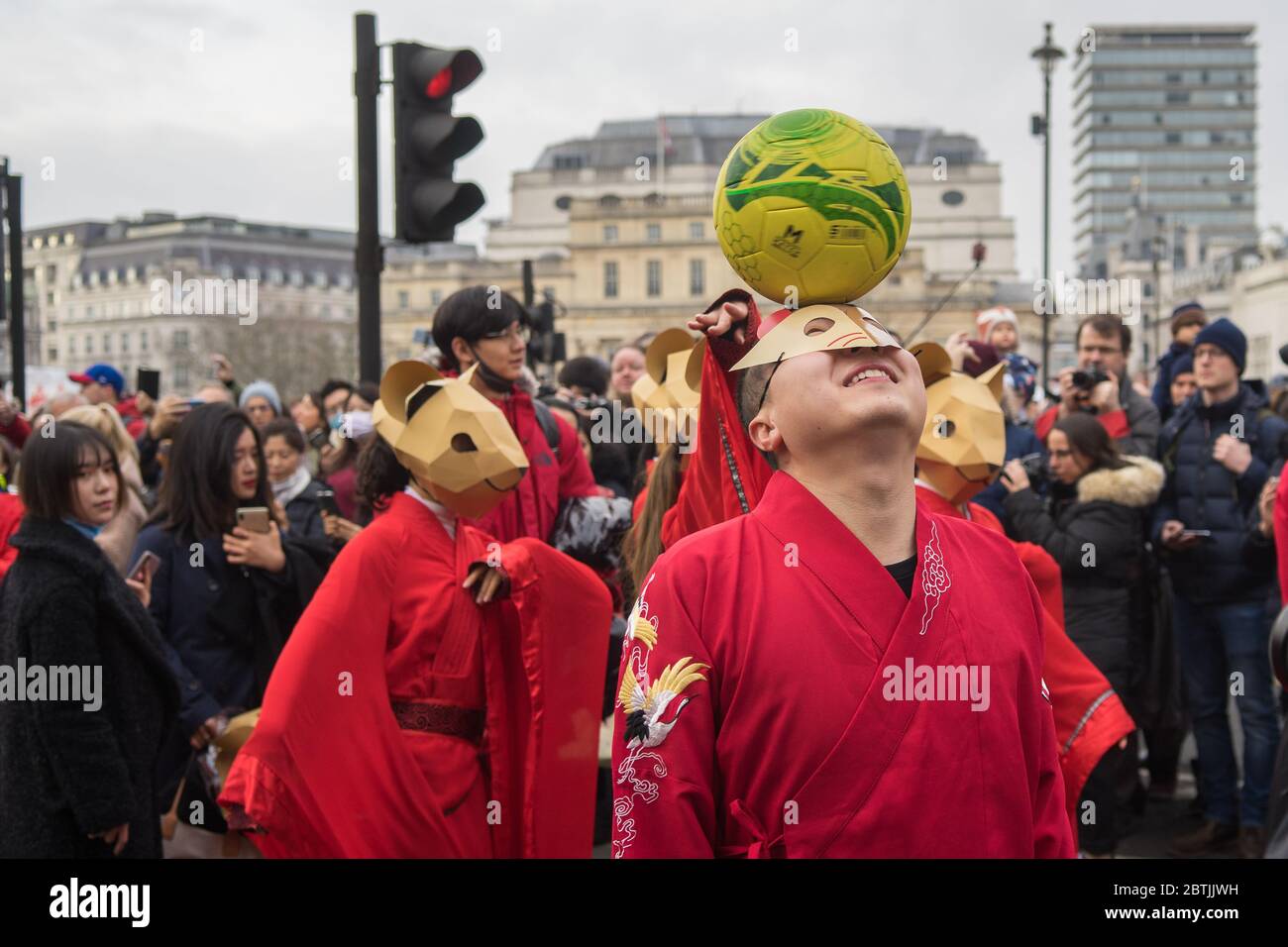 Mann, der einen Fußball anführt, während er eine Rattenmaske trägt, um das Jahr der Ratte zu feiern. Parade Zur Chinesischen Neujahrsfeier. London Stockfoto