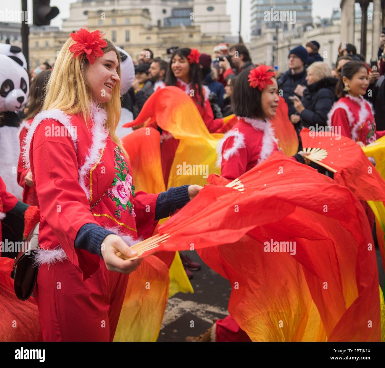 Lady in rotem Kostüm mit roter Blume im Haar. Parade Zur Chinesischen Neujahrsfeier. London Stockfoto