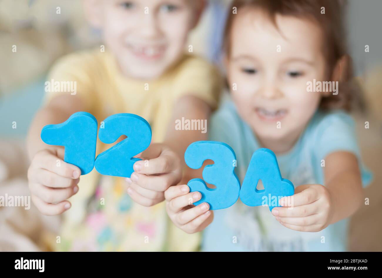 Pädagogische bunte Zahlen Figuren in einem Kind Hände. Unterweisung von Kindernummern. Glückliche Kinder zeigen Zahlen. Stockfoto