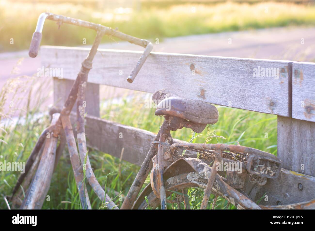 Ein altes verlassene rostige Fahrrad parkte gegen Holzzaun. Altmodische klassische Fahrrad steht vergessen entlang eines Radweges. Aus dem Graben gefischt Stockfoto