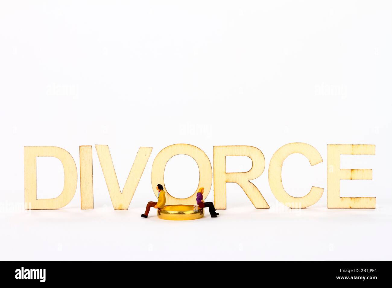 Miniatur Figur Paar saß auf einem Ehering mit dem Wort Scheidung Stockfoto