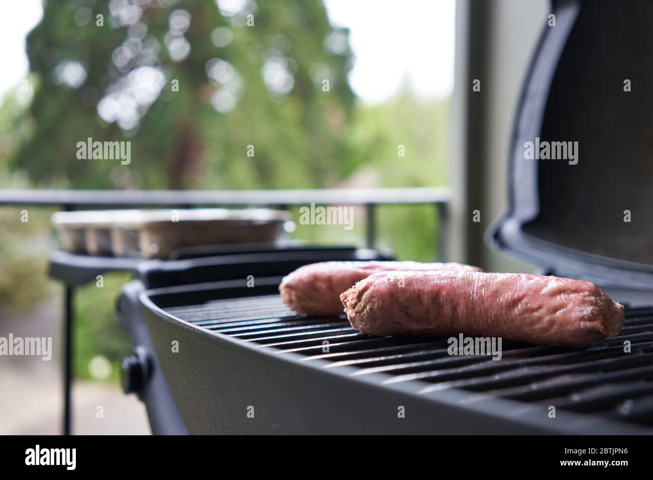Auf pflanzlicher Basis werden neben Fleischwürsten auf dem Grill Würstchen serviert. Selektiver Fokus auf einen der veganen Wurstenden. Stockfoto