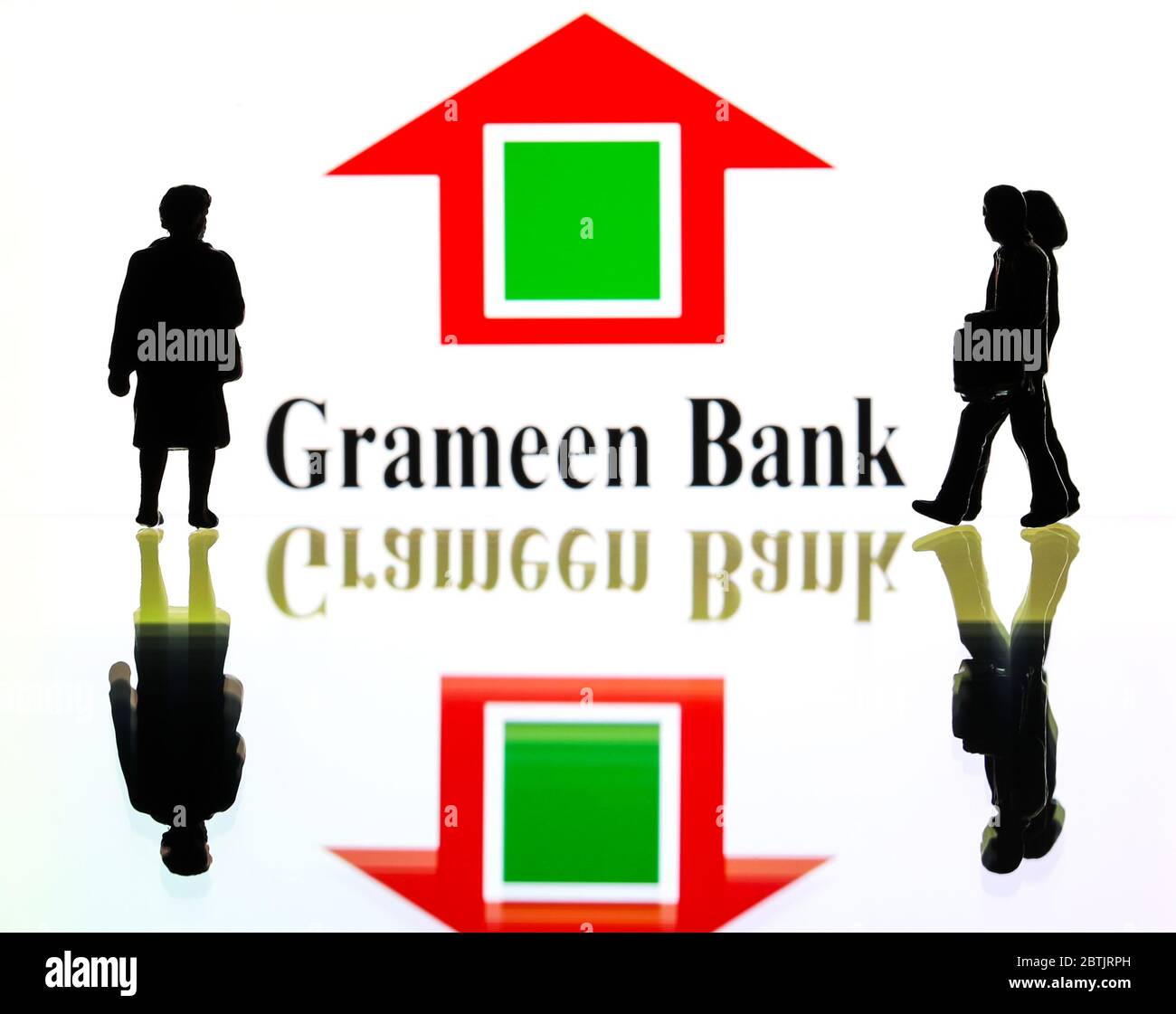 Silhouetten vor dem Logo für Grameen Bank (nur redaktionelle Verwendung) Stockfoto