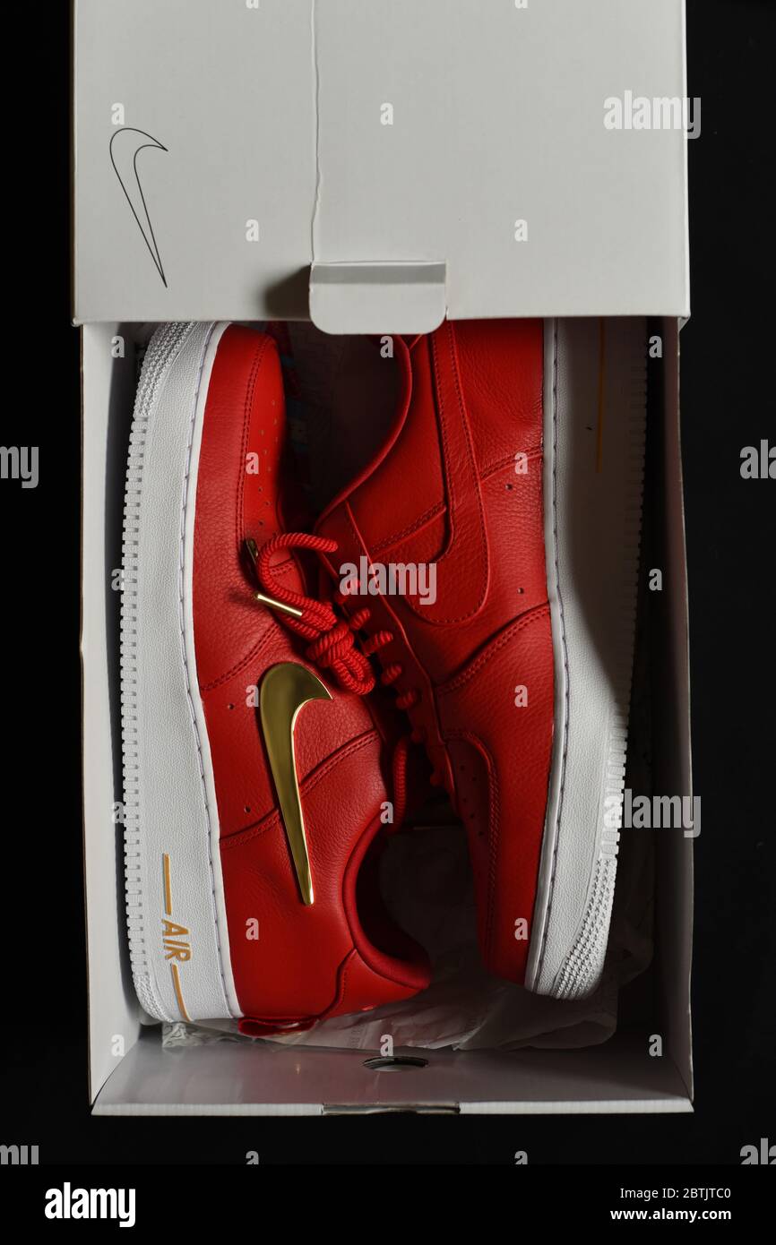 Sammelbare sportliche Sneaker von Nike, ein Air-Schuhmodell mit rotem Oberteil, weißer Sohle und goldenen Akzenten, darunter das berühmte Swoosh-Logo und die Spitze Stockfoto