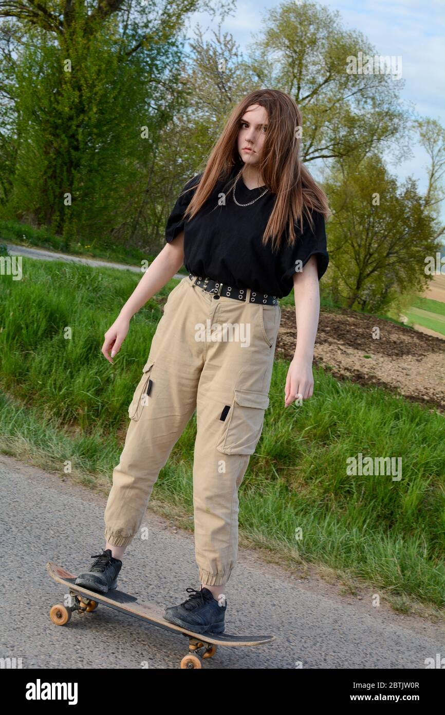 Junges Mädchen reitet ein Skateboard auf einer Landstraße in grüner Natur Stockfoto