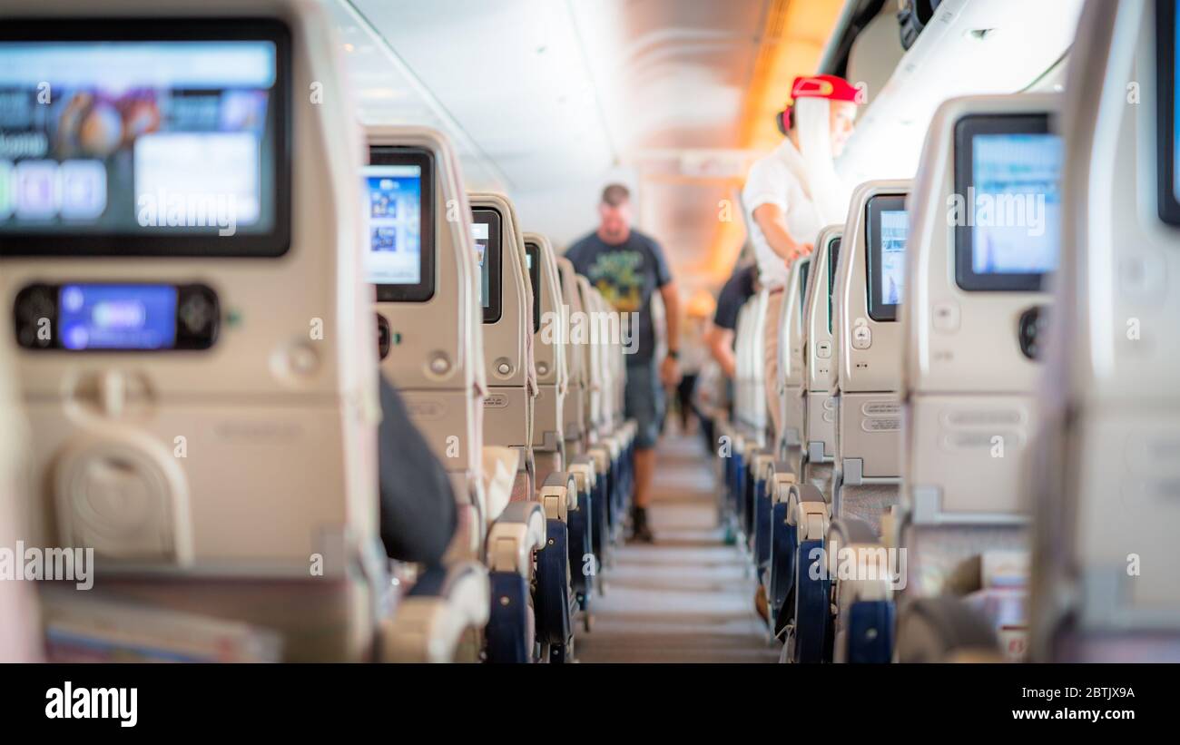 Innenraum der großen Passagiere Flugzeug mit Menschen auf Sitzen und Stewardess in Uniform zu Fuß den Gang. Stockfoto